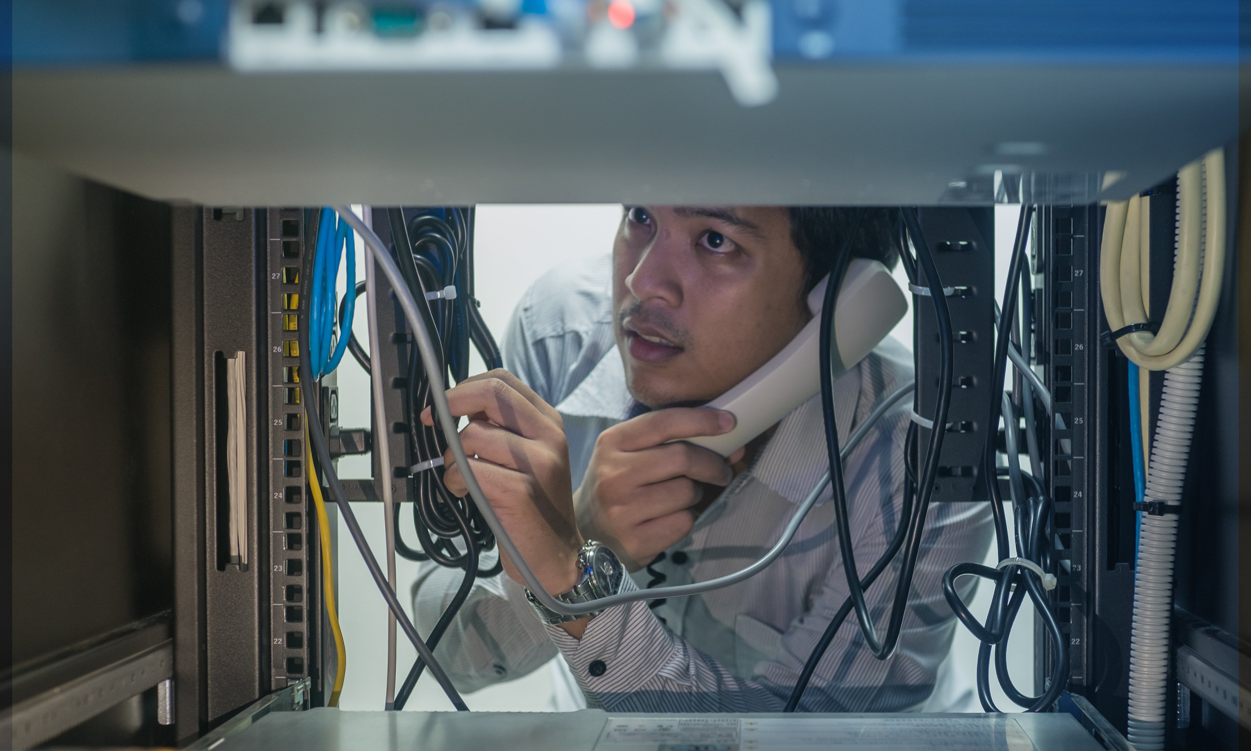 Man troubleshooting in data center with consult by telephone